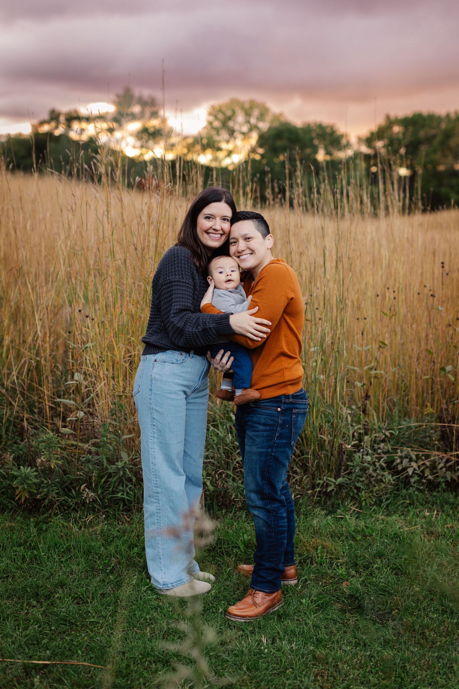 Two individuals embracing in a golden field at sunset surrounded by tall grass. Twin Cities, Decorah Iowa family photography.
