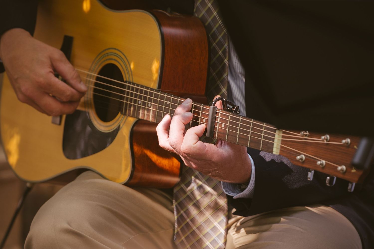 Close-up of hands strumming an acoustic guitar during a wedding ceremony performance.