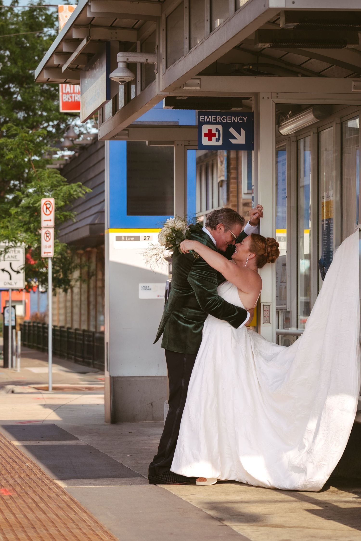 Bride and groom sharing romantic kiss outside emergency entrance on wedding day.