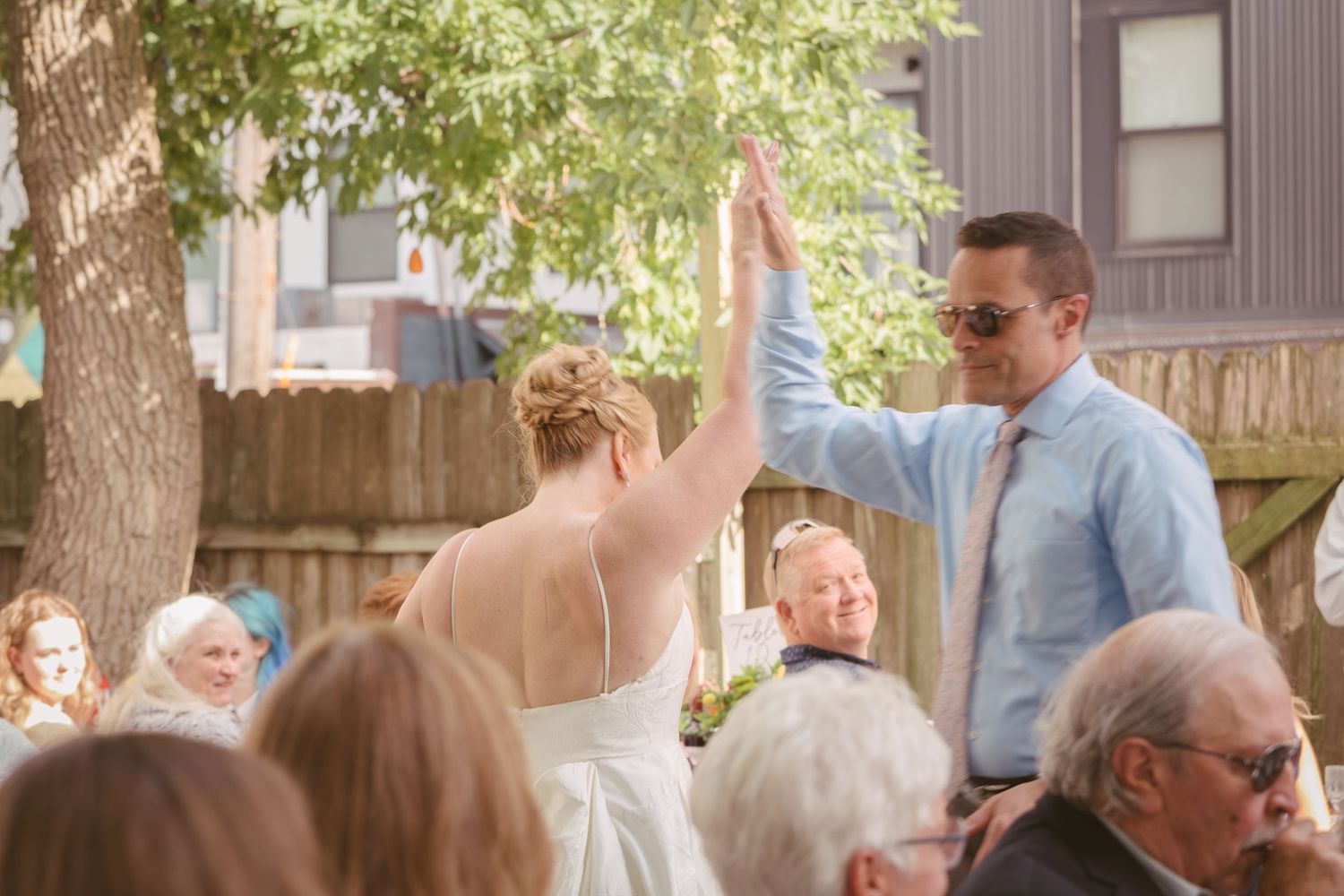 Bride and groom share a high five during their outdoor backyard wedding ceremony.