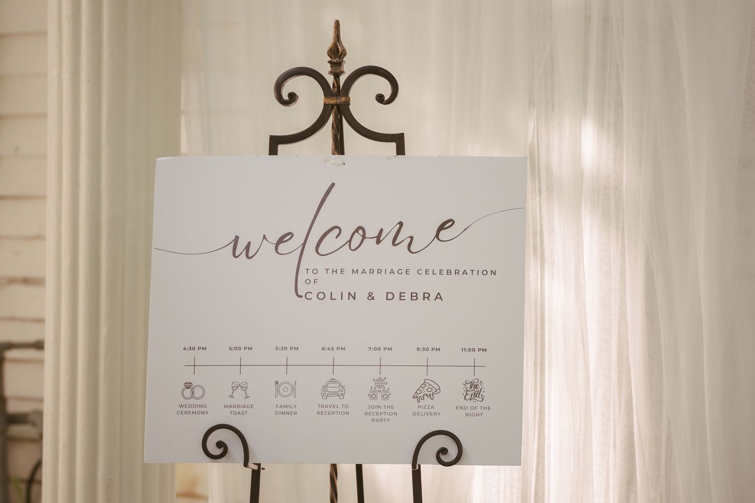 Elegant wedding welcome sign on a black easel for Colin and Debra's marriage celebration with event timeline icons.