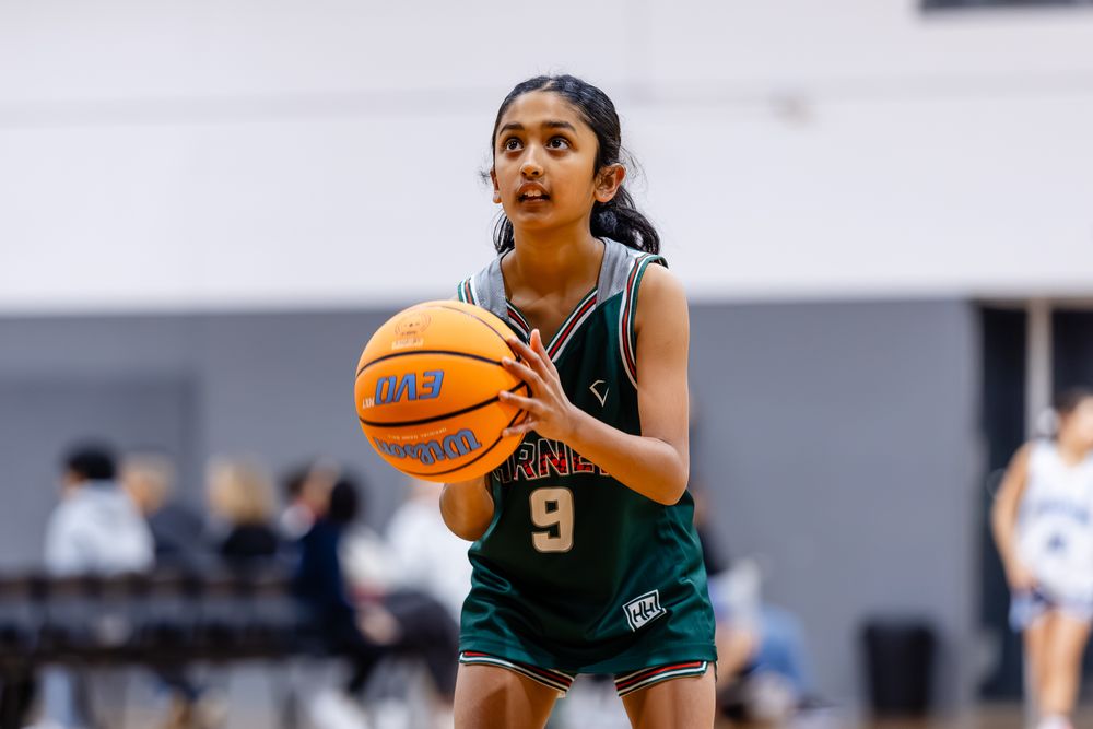 Young female basketball player wearing jersey number 9 prepares to shoot during an indoor basketball game.