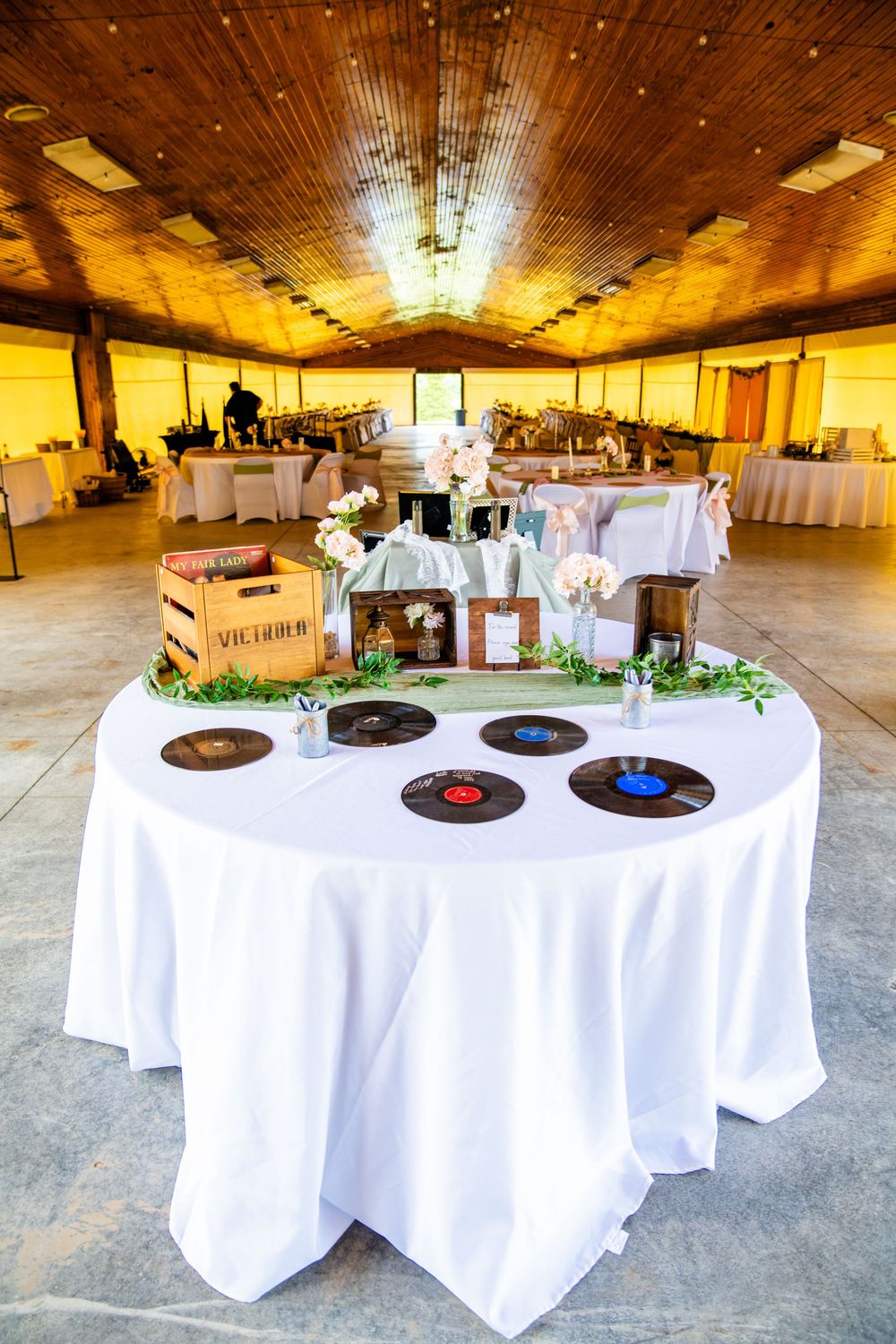 Elegant wedding reception hall with vinyl records displayed on white tablecloth welcome table.