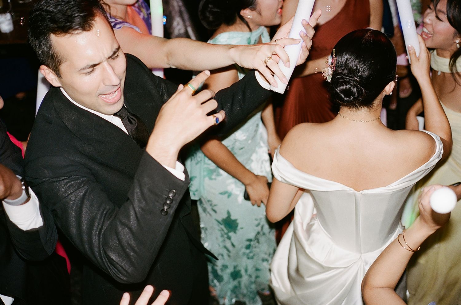 Wedding reception guests dancing and celebrating on a crowded dance floor.