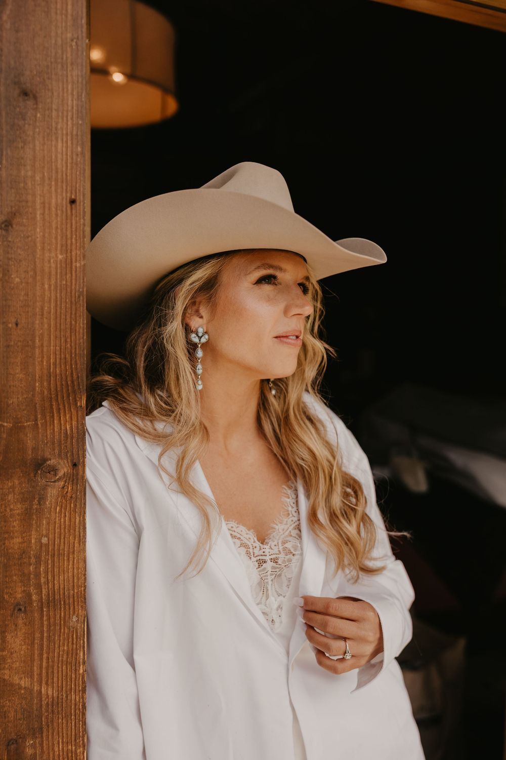 Bride looks off in her Stetson Hat and Turquoise on her Wedding day at Copper Rose Ranch Cabin by Local Wedding Photographer