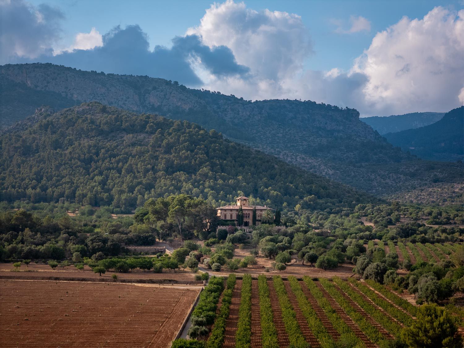 a typical mallorcan finca Son Burguet surrounded by the mountains with an intimate wedding ceremony set up in front of it