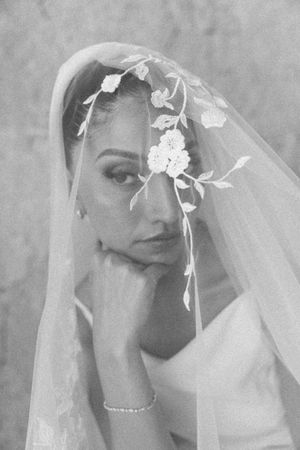 Close-up black and white portrait of bride draped in floral embroidered wedding veil.