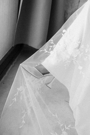 Close-up black and white photo of delicate floral embroidered bridal veil fabric detail.