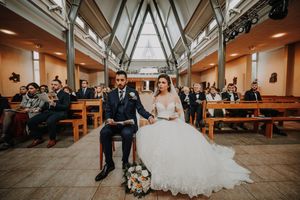 Bride and groom seated at church altar during wedding ceremony with guests in pews.