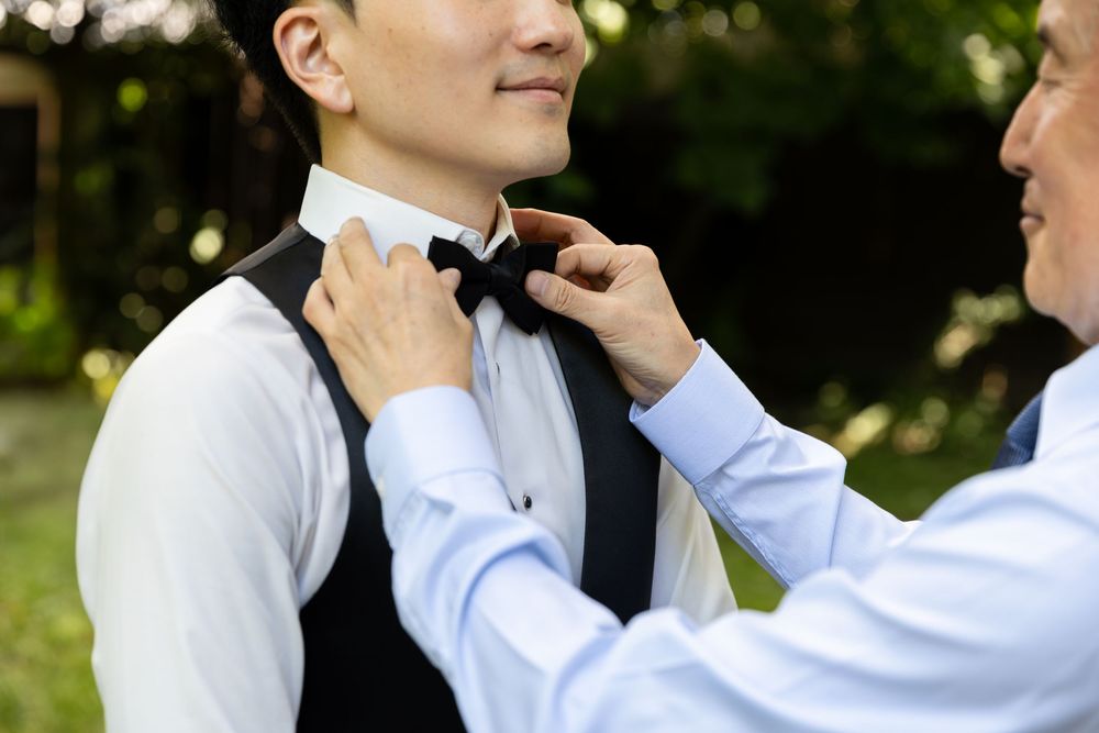 Close up photo of grooms father adjusting the grooms tie in the backyard of their home on the morning of their wedding in London, Ontario.