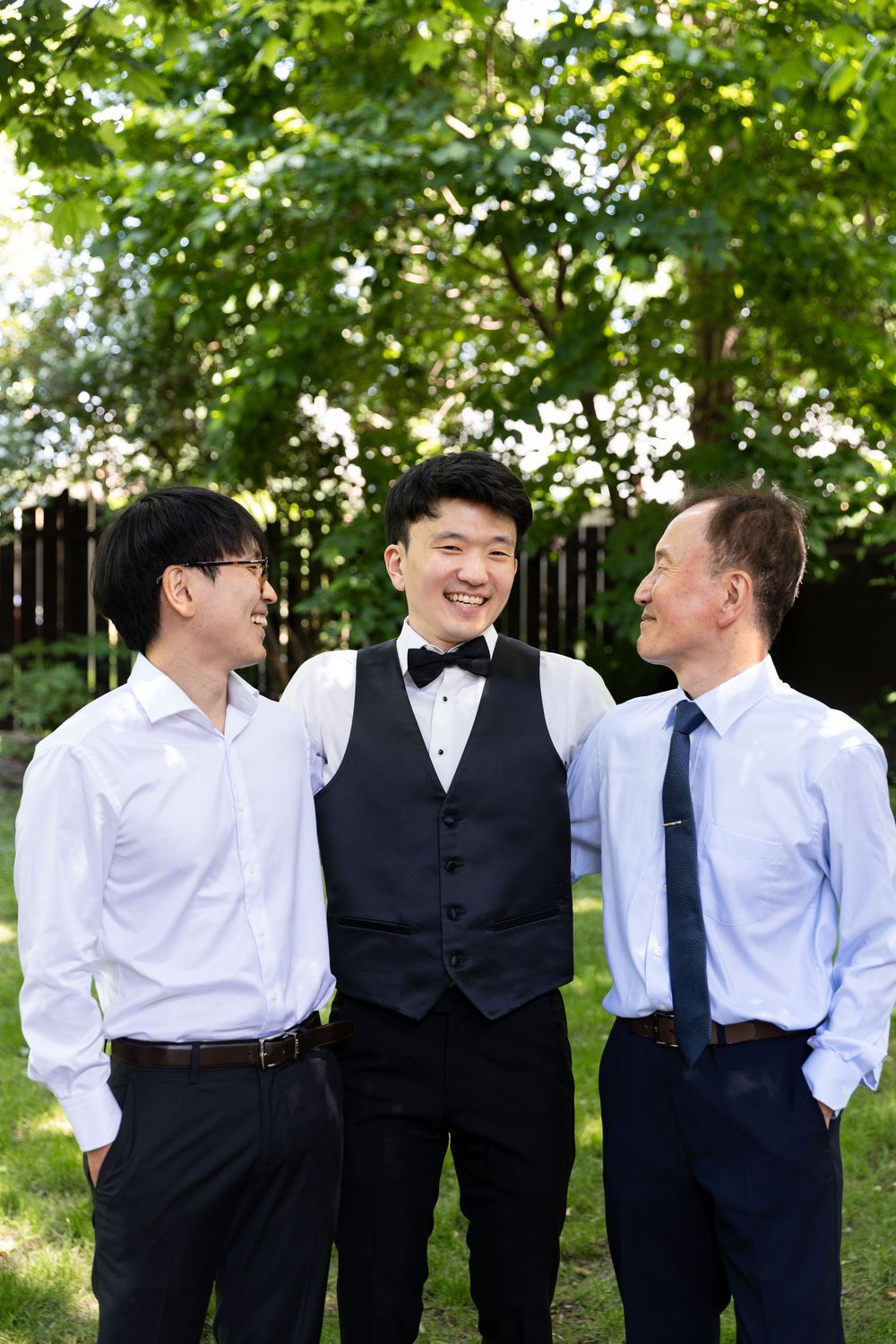 Groom laughing with his father and brother surrounded by greenery on the morning of their london, ontario wedding.