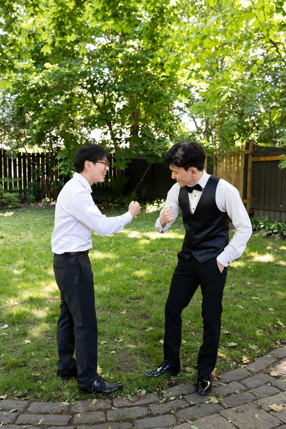 Groom and his brother standing in his backyard doing a special handshake on the morning of their london, ontario wedding.