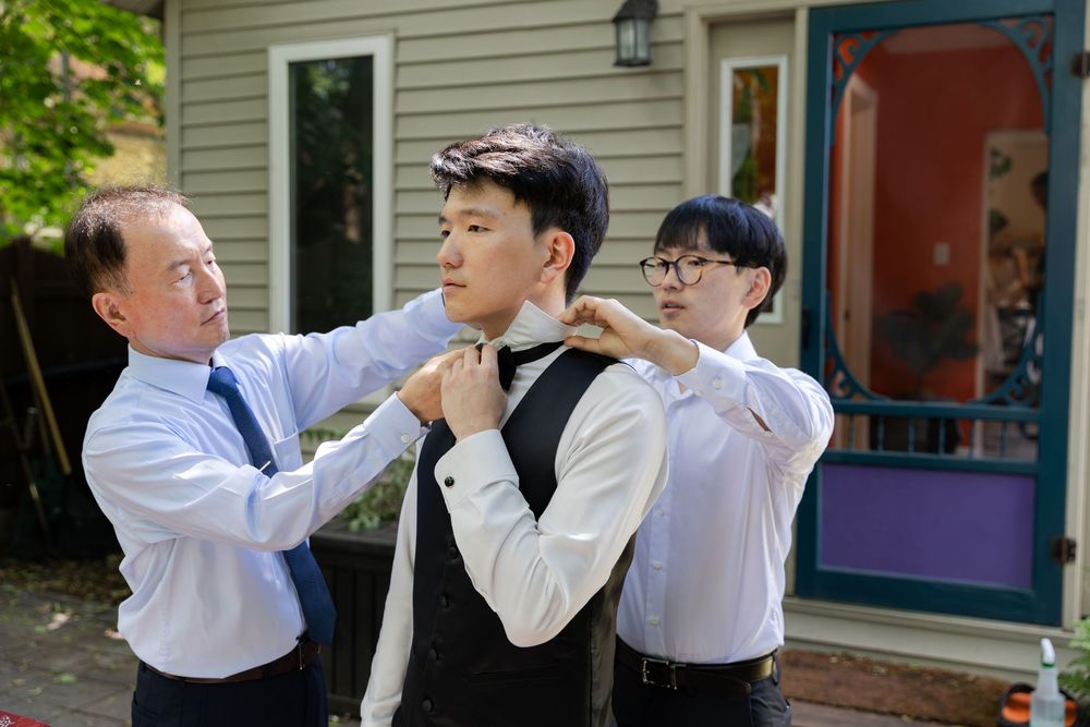 Grooms dad and brother readjust the grooms bowtie and collar on the morning of their london, ontario wedding.