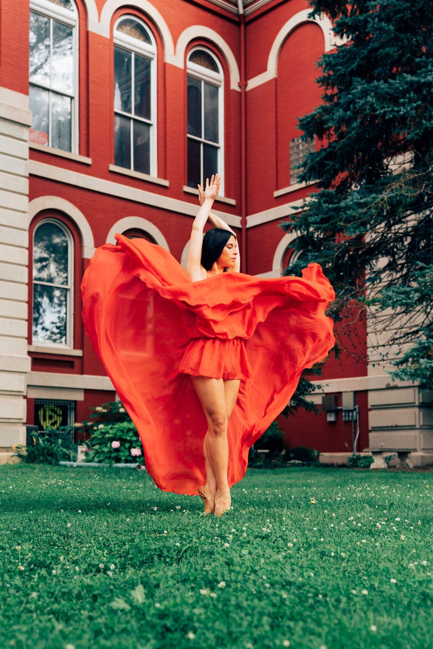 Professional senior portrait photography of dancer's red skirt billowing in the air before the Old Lake County Courthouse crown point, IN