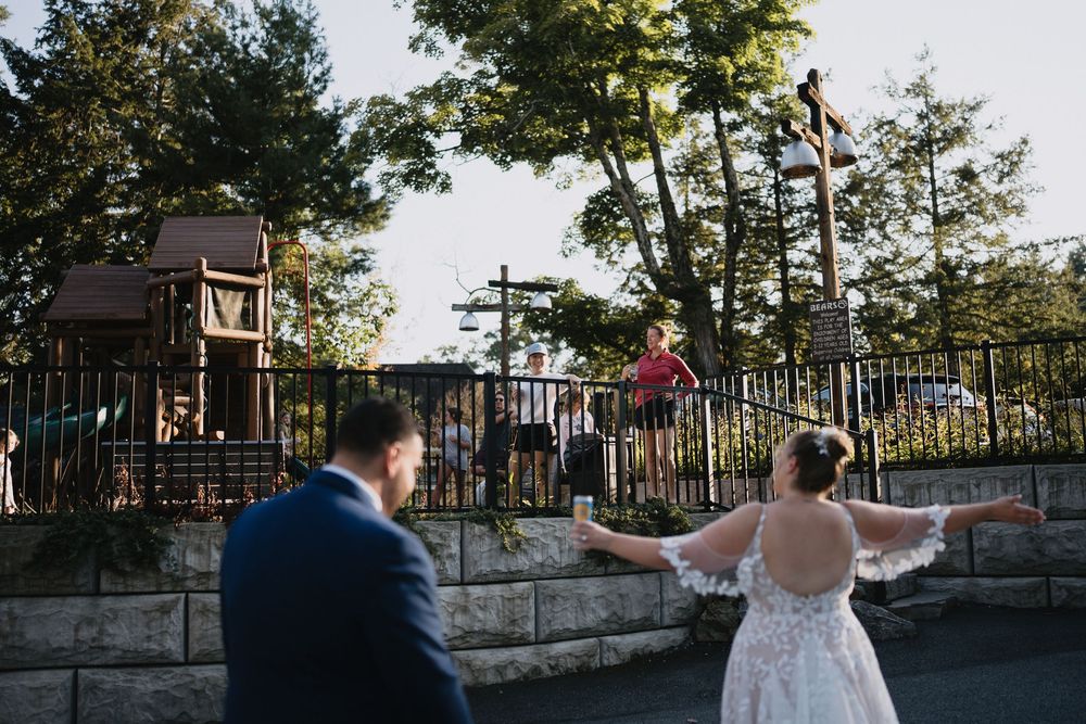 Bride and groom hold hands outdoors near a playground on their wedding day.