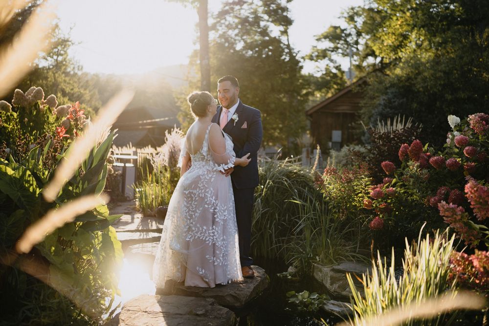 Bride and groom share a romantic moment in a lush garden at golden hour, surrounded by colorful blooms.
