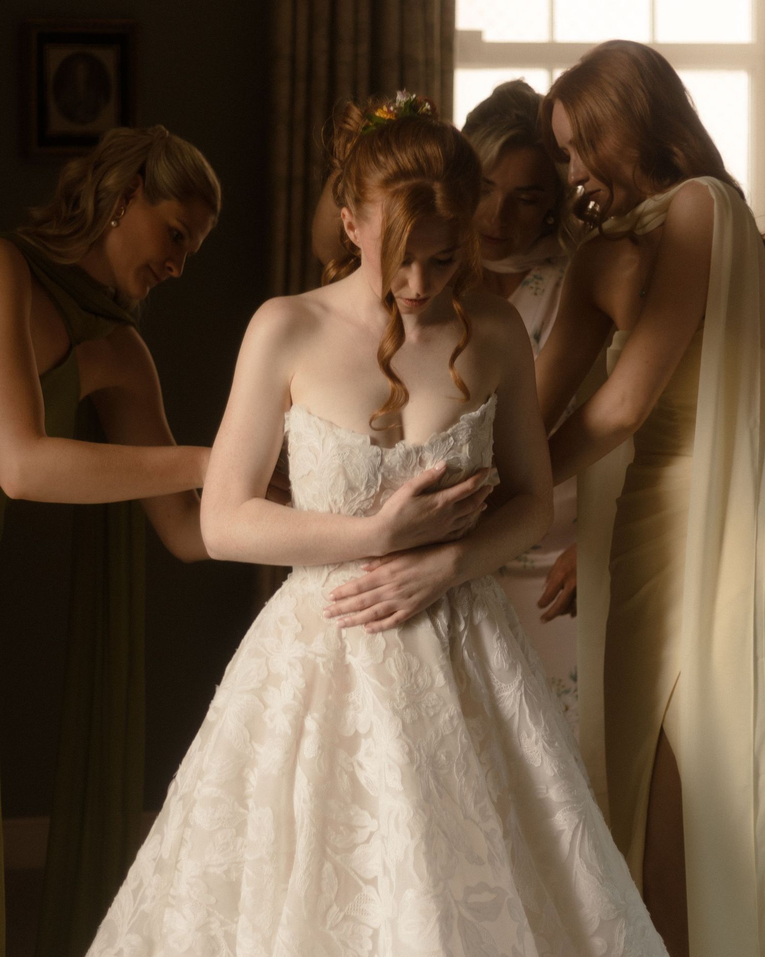 A cheerful wedding party celebrates on the grounds of a historic stone manor house in muted sepia tones.