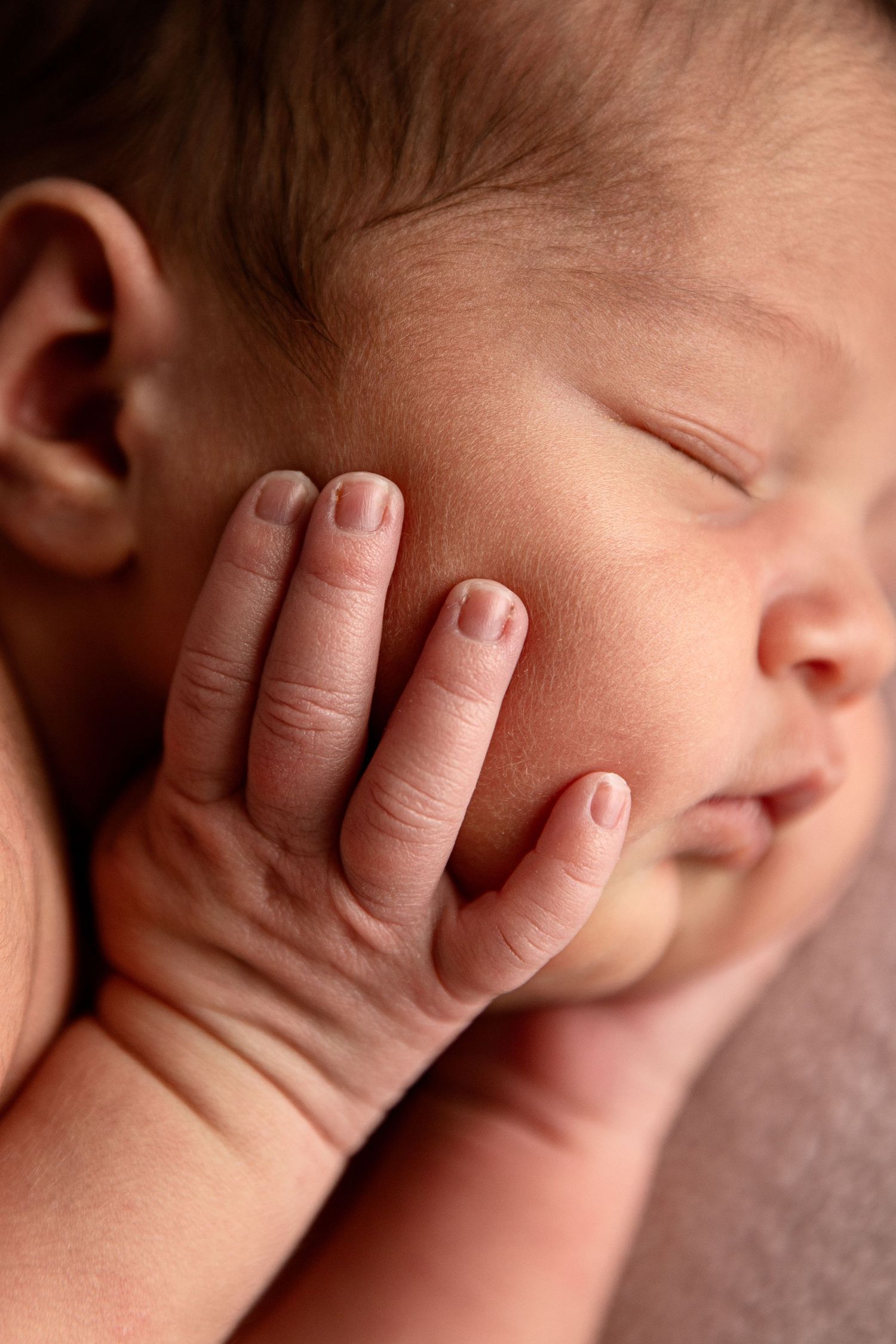 Professional posed newborn baby in Dubai baby photoshoot -close up shot of hand on cheek