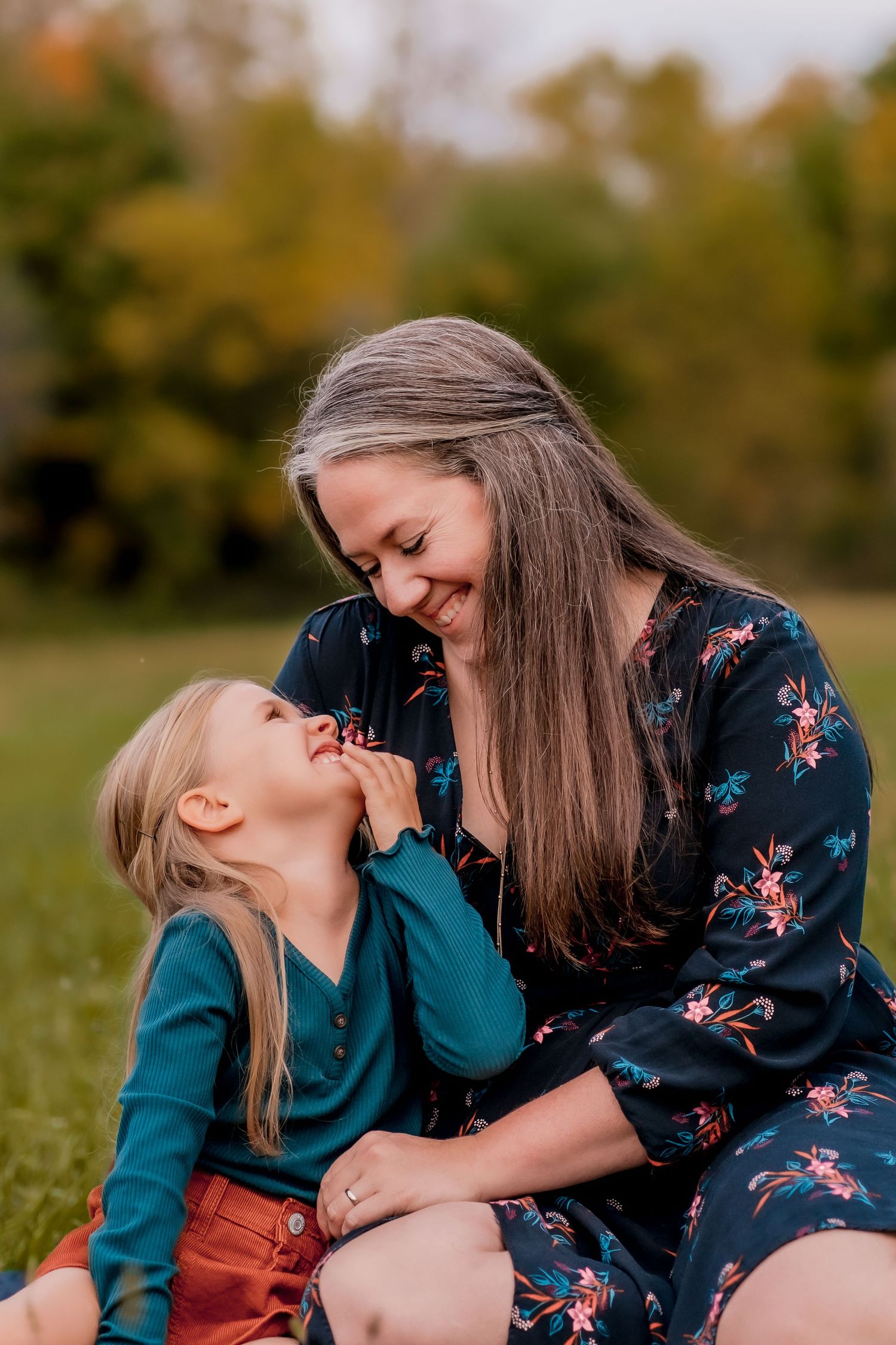 Mother and daughter share sweet moment in autumn field with golden light.