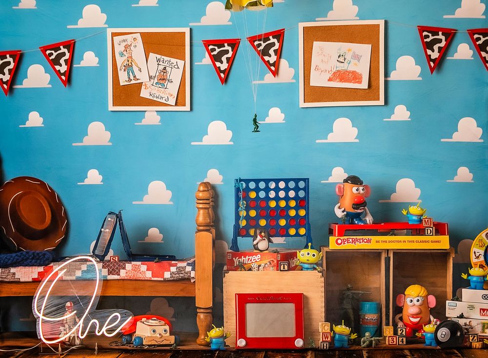 Toy Story themed classroom display features colorful cloud wallpaper and wooden shelving with character decorations.