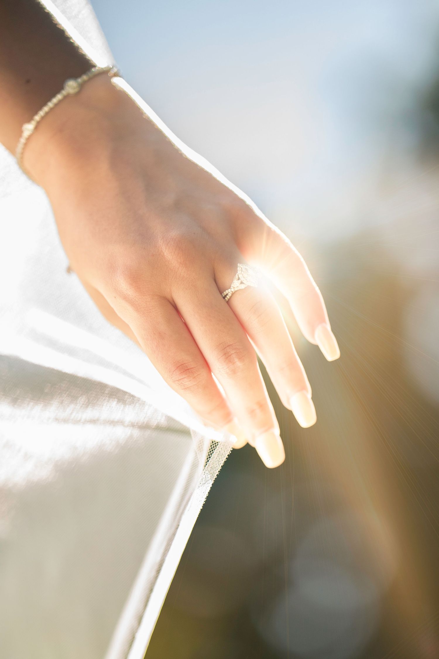 Close-up view of hands holding white fabric in soft natural lighting.