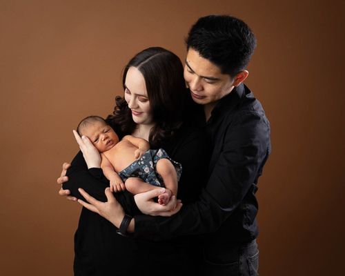 Romantic couple embraces in a series of intimate poses against a dark brown studio backdrop.