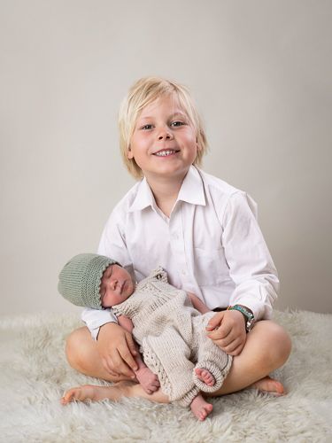 A series of five connected photos showing a young child in white shirt sitting with a newborn baby in knitted clothes.