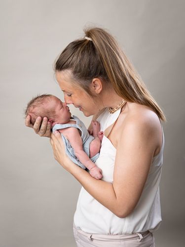 A series of four connected photos shows a parent in white clothing holding and bonding with their newborn baby.