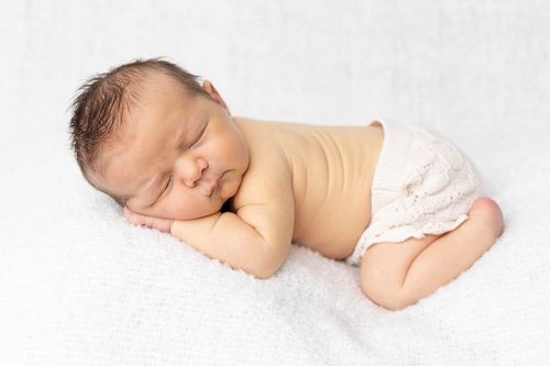 Three artistic black and white photos of sleeping newborn on white backdrop.