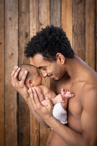 A tender moment captured in sequence showing a parent lovingly cradling and kissing a newborn baby against a wooden wall backdrop.