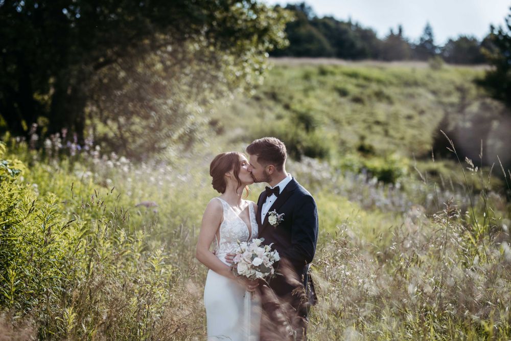 Romantic wedding photo of couple kissing in a wildflower meadow.