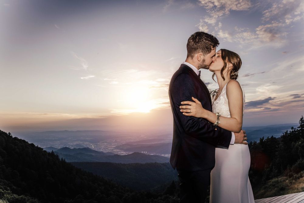 Dramatic sunset wedding portrait of couple embracing on a mountaintop.