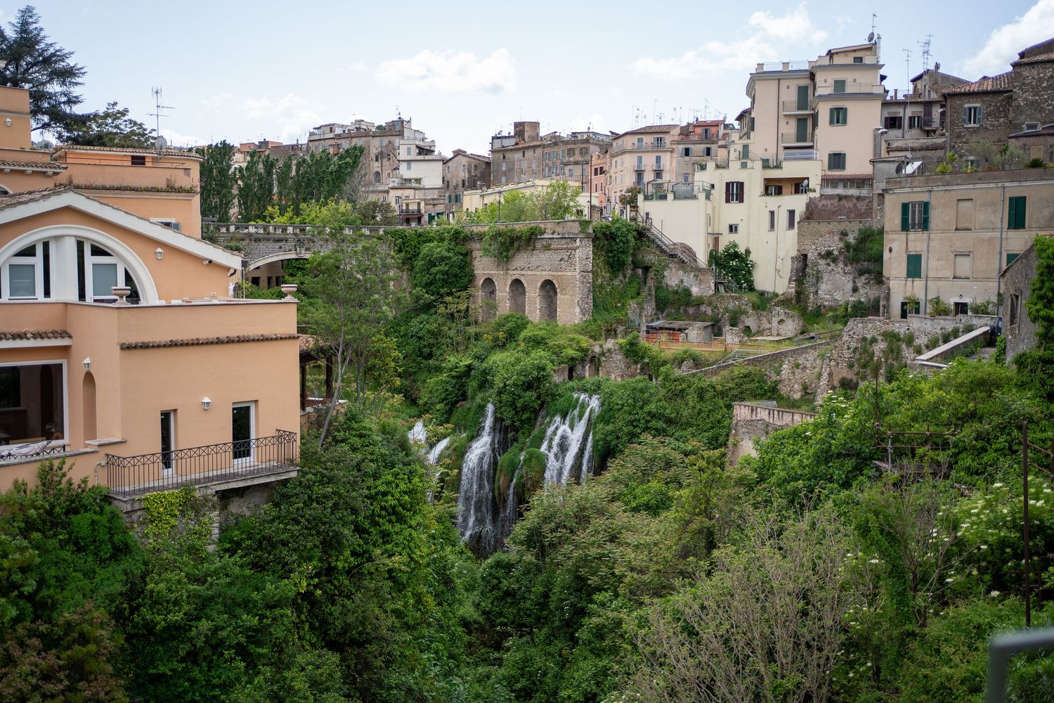 Historic buildings perch above cascading waterfalls in the hillside town of Tivoli, Italy.