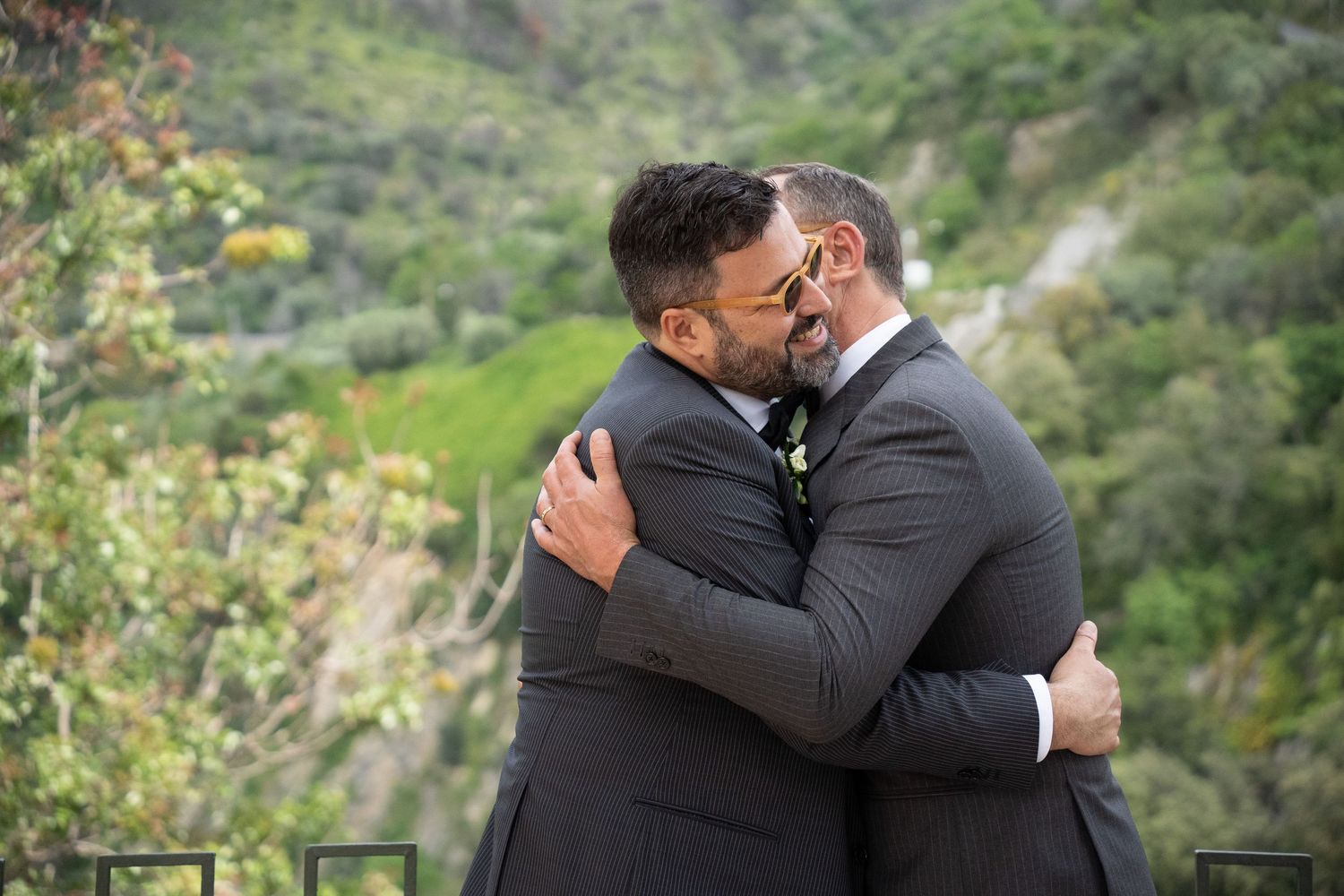 Two people share an intimate moment during their outdoor wedding ceremony in a lush natural setting.