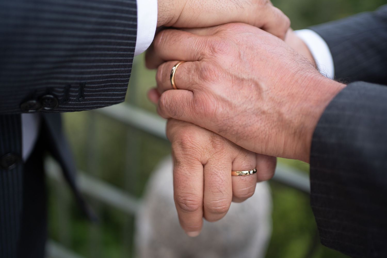 Close-up shot of hands shaking in formal business attire against a blurred outdoor background.