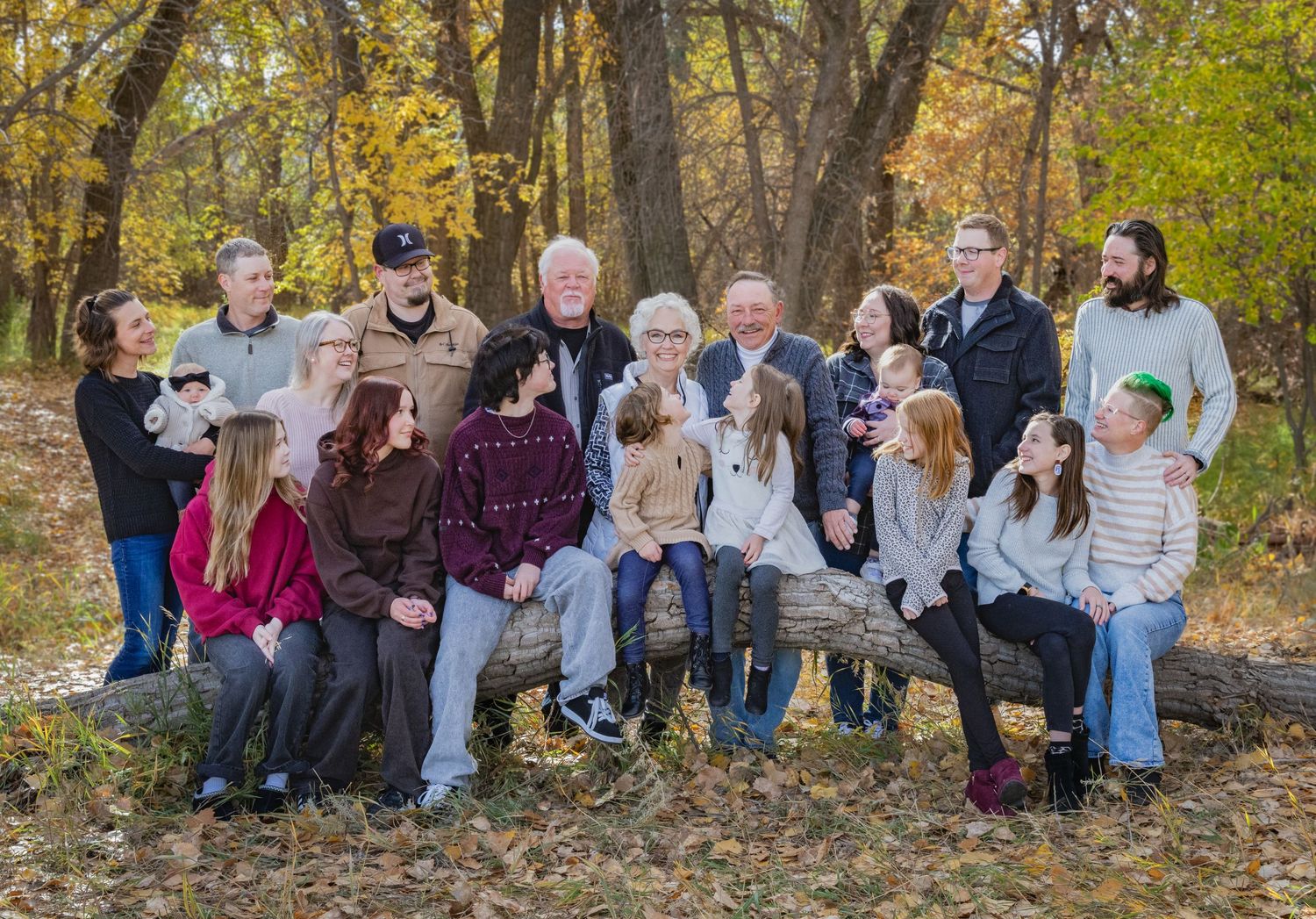 a big family group all gathered around an older couple, all smiling at each other.Family lifestyle session in Alberta by Creation Photograph