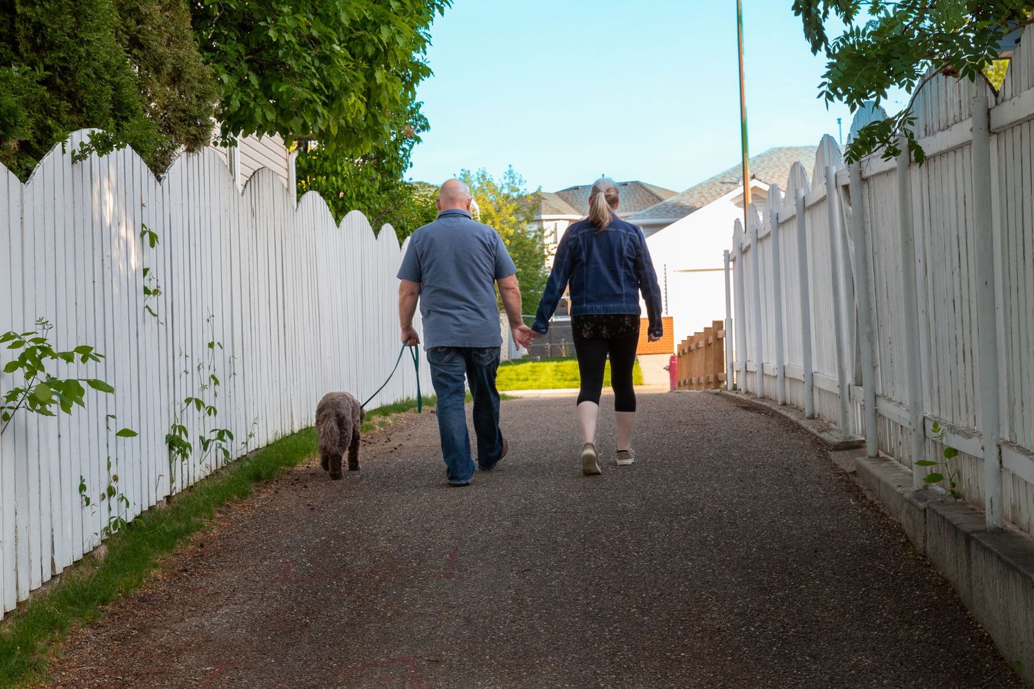 a couple walks on a path with his dog.