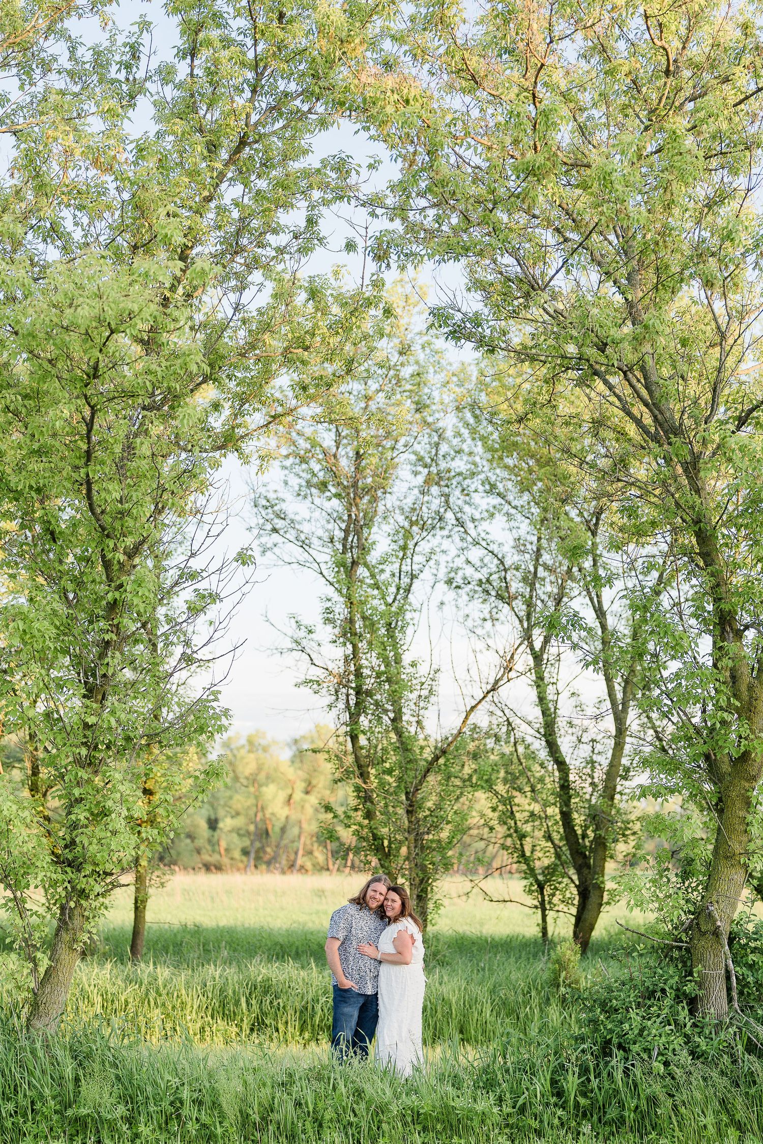 Engaged couple smiling under a tree during their Kenosha engagement session.