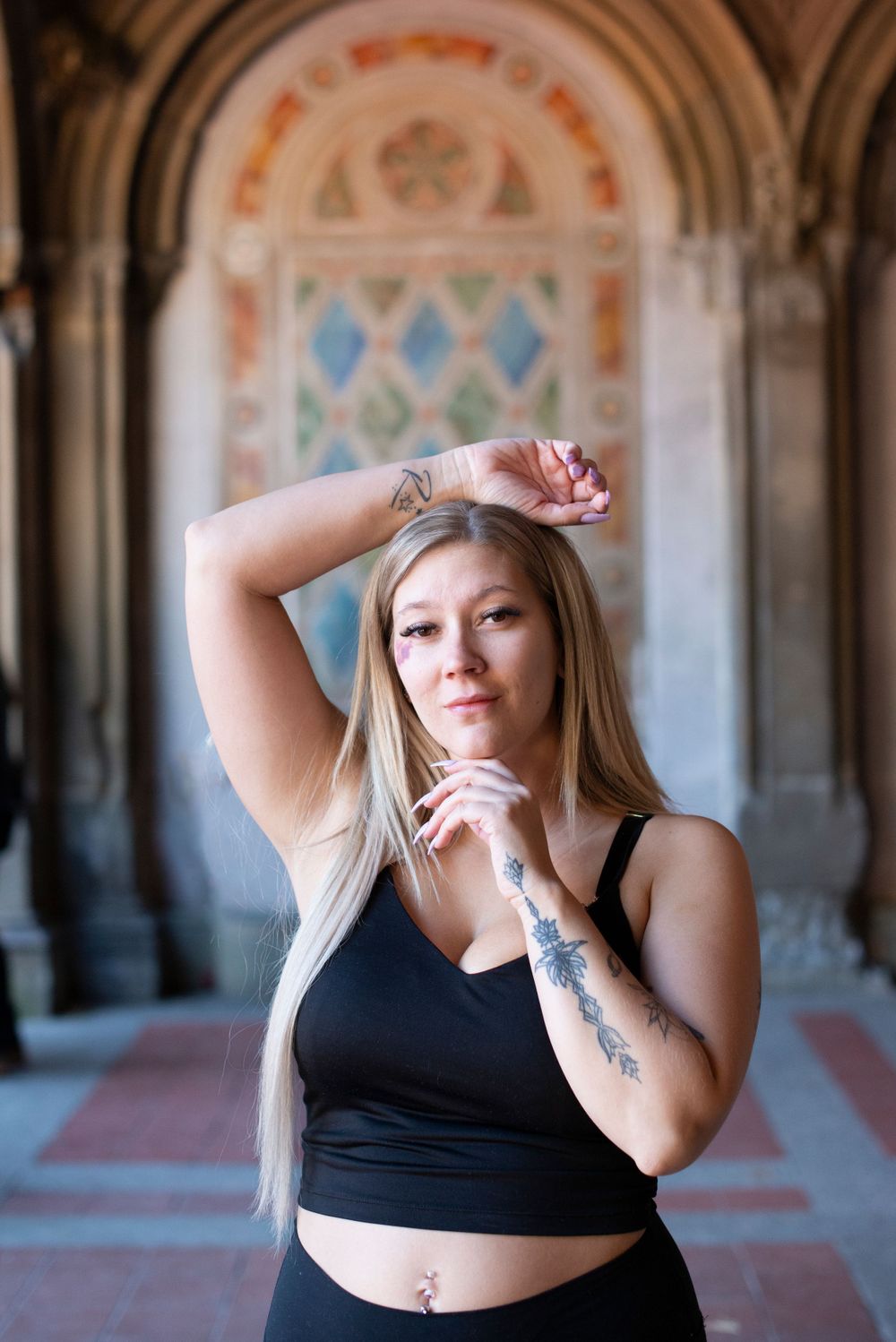 Dancer poses gracefully under decorative arched passageway with geometric patterns.