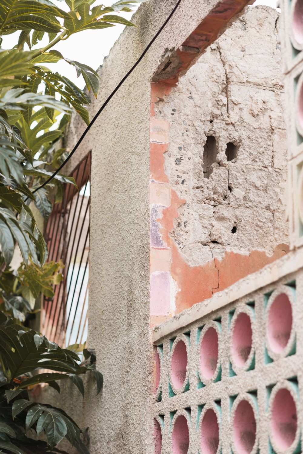 Pink and green architectural details of a weathered Mediterranean-style wall with ornate cutouts.
