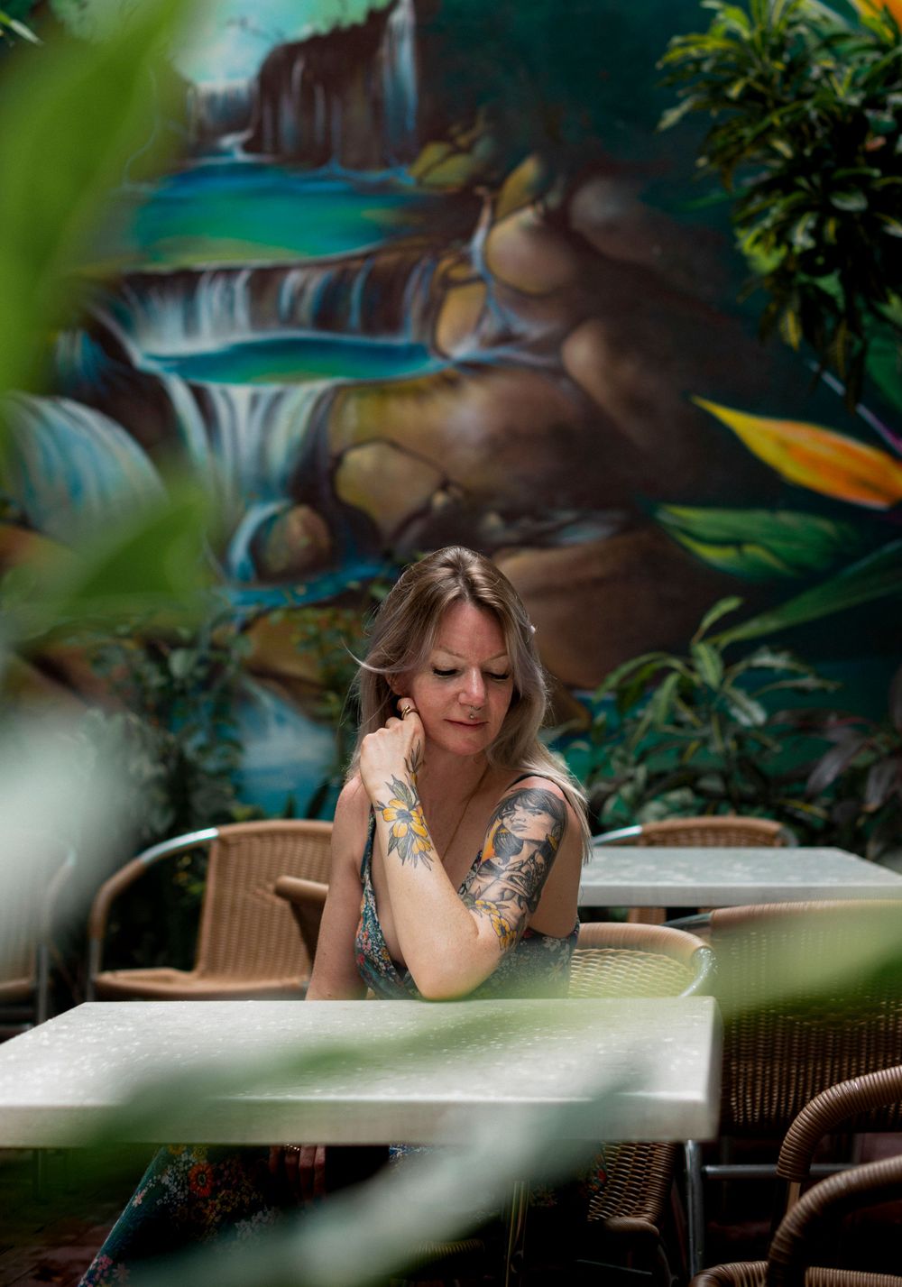 A tranquil outdoor dining setup against a tropical waterfall mural backdrop.
