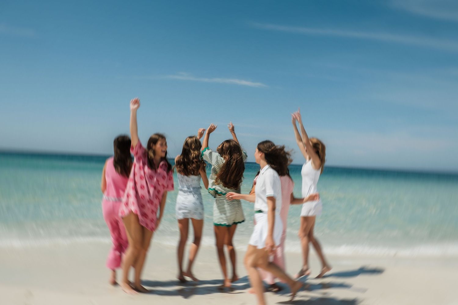 People gathered on a tropical beach with turquoise water and clear blue skies.