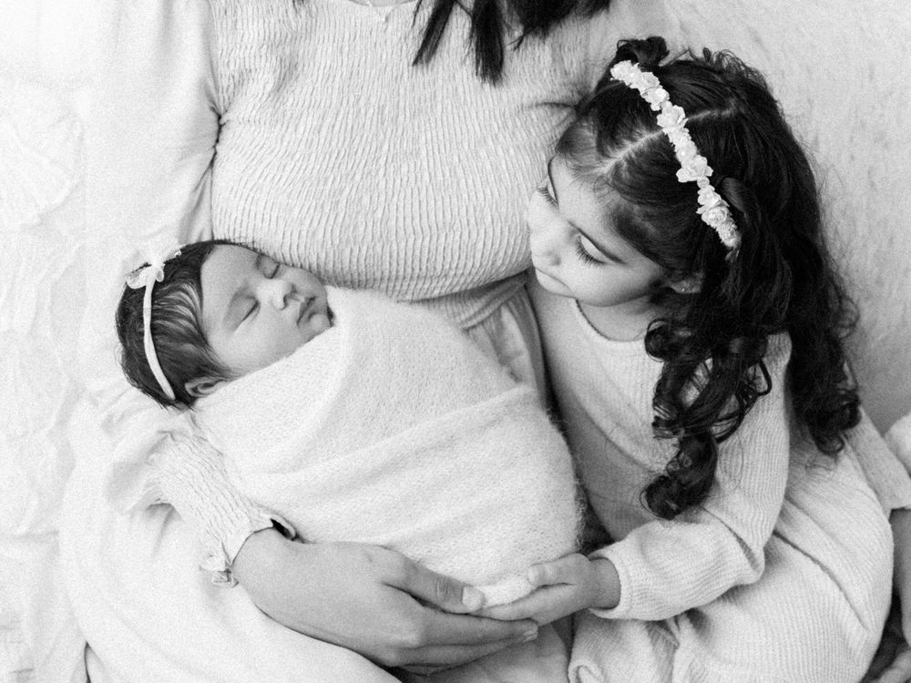 Black and white image of siblings sharing tender moment.
