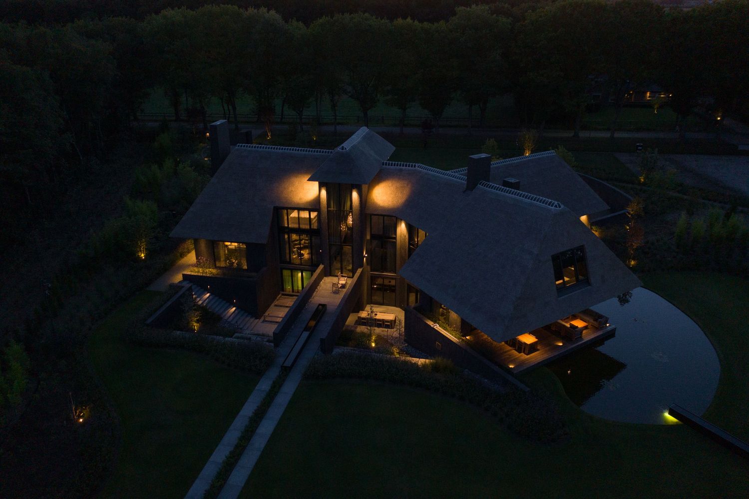 Aerial night view of illuminated luxury resort buildings surrounded by landscaping.