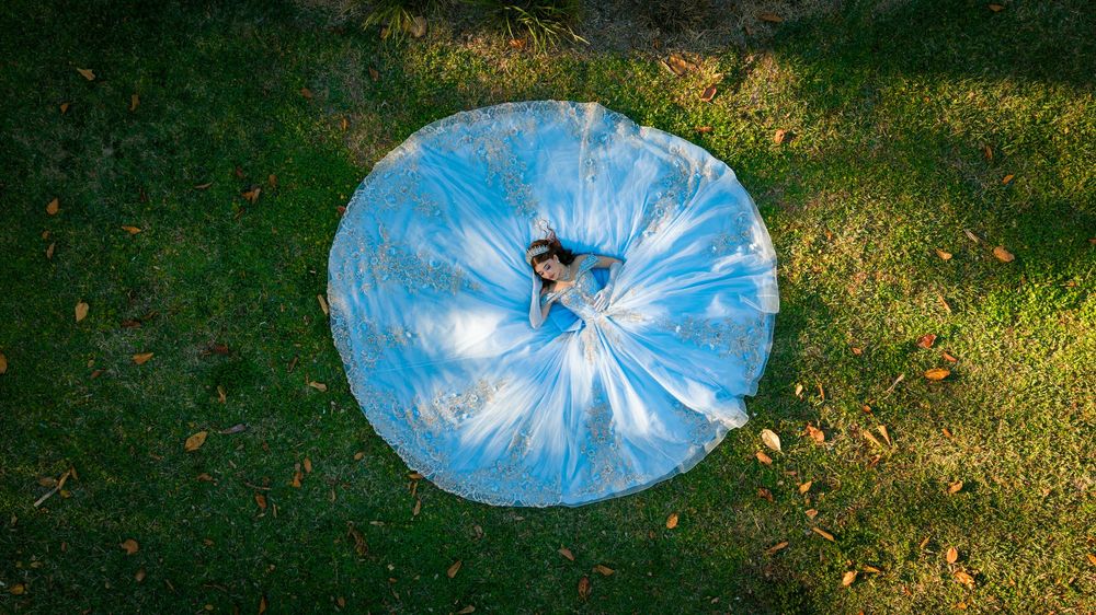 Aerial view of person lying inside large blue transparent bubble ball on green grass.