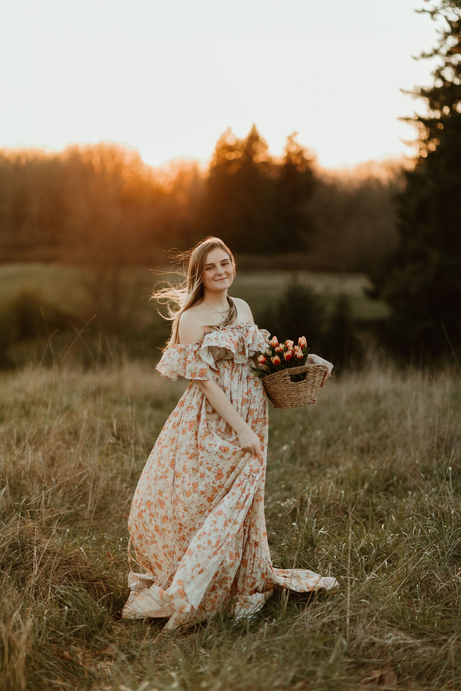 Expecting mother poses with basket of tulips and flowers in open field near ocean in Seattle, WA