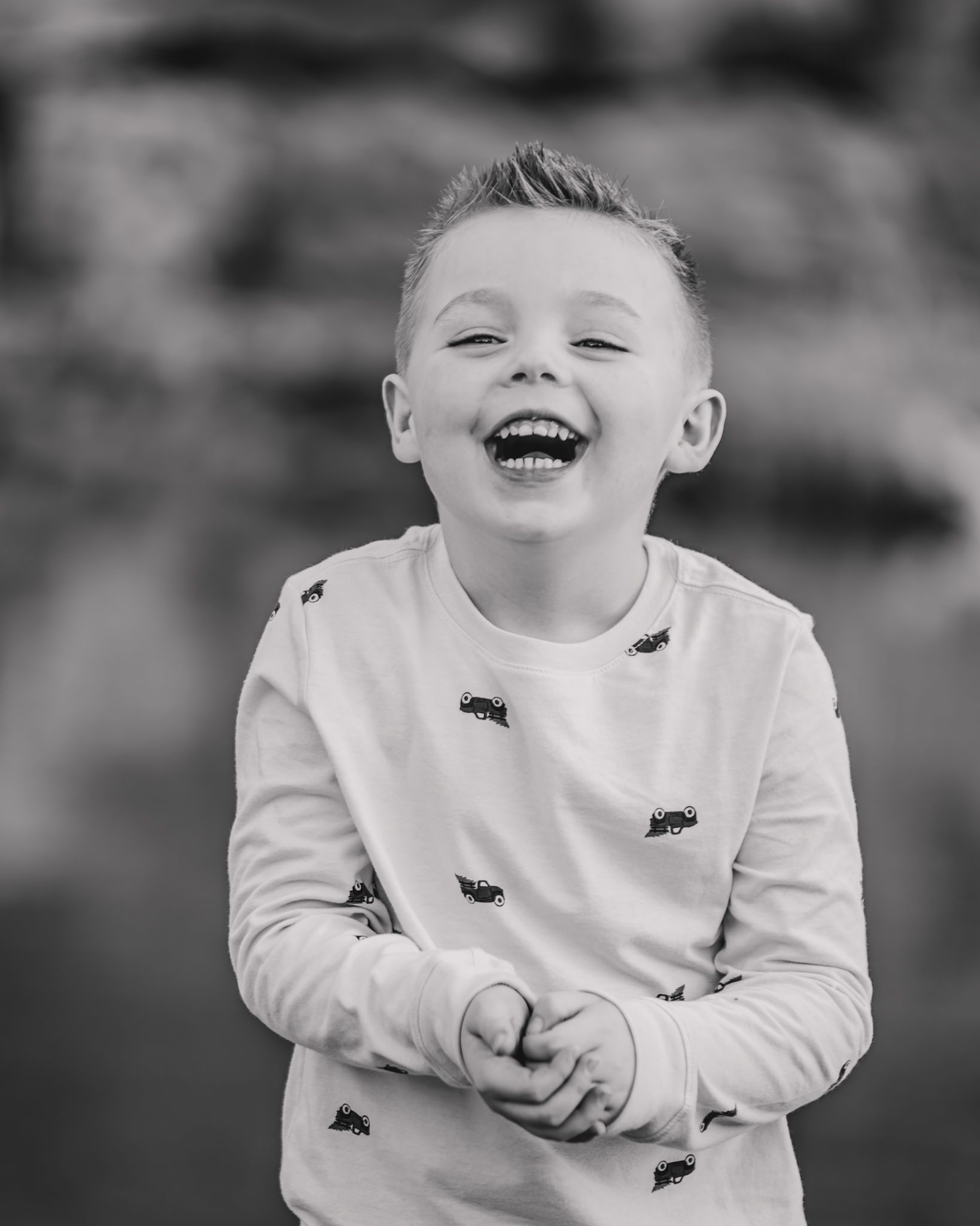 A child wearing a white sweater shows pure joy and laughter in a series of black and white candid portraits.