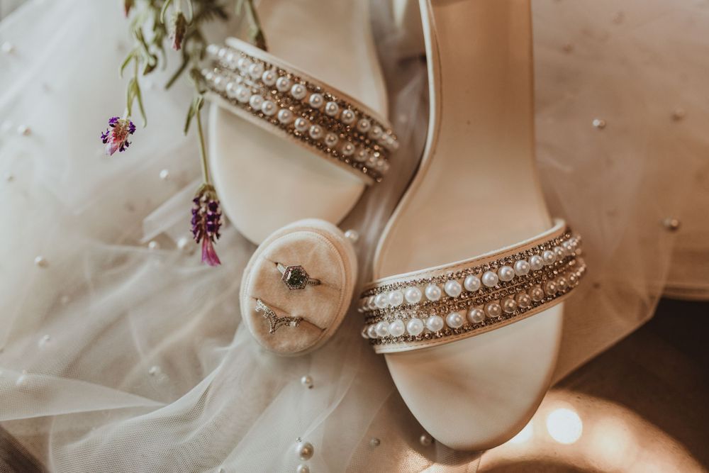 Elegant bridal shoes with pearl detailing and delicate flowers on white fabric.