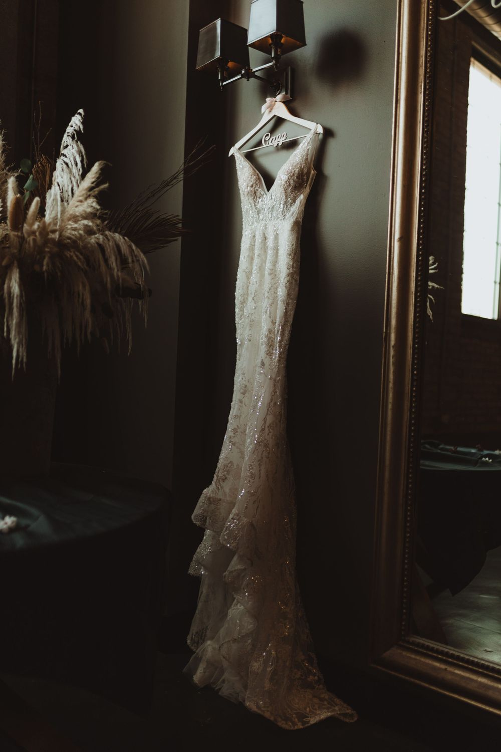 Lace wedding dress hanging in a dark room with dramatic lighting.