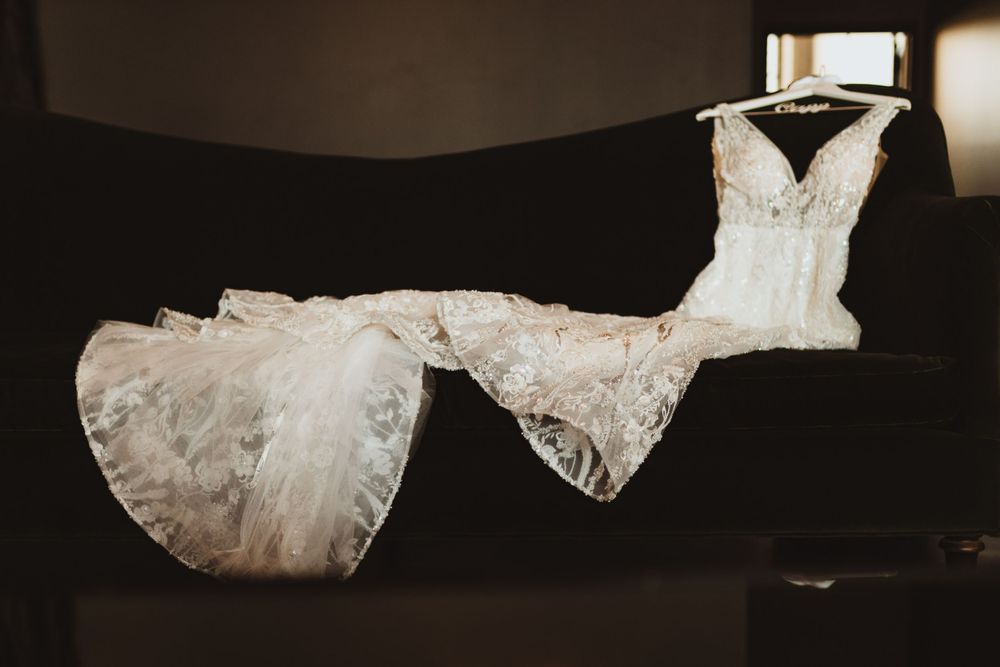 White wedding gown with delicate lace details displayed against a dark backdrop.